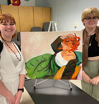 Two happy female students posing next to a beautiful painting