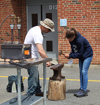 Kathryn learning how to weld metal during an outdoor demonstration